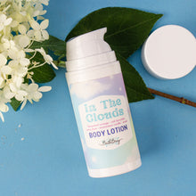 Load image into Gallery viewer, Body lotion bottle labeled &#39;In The Clouds&#39; on a blue background with flowers and leaves.