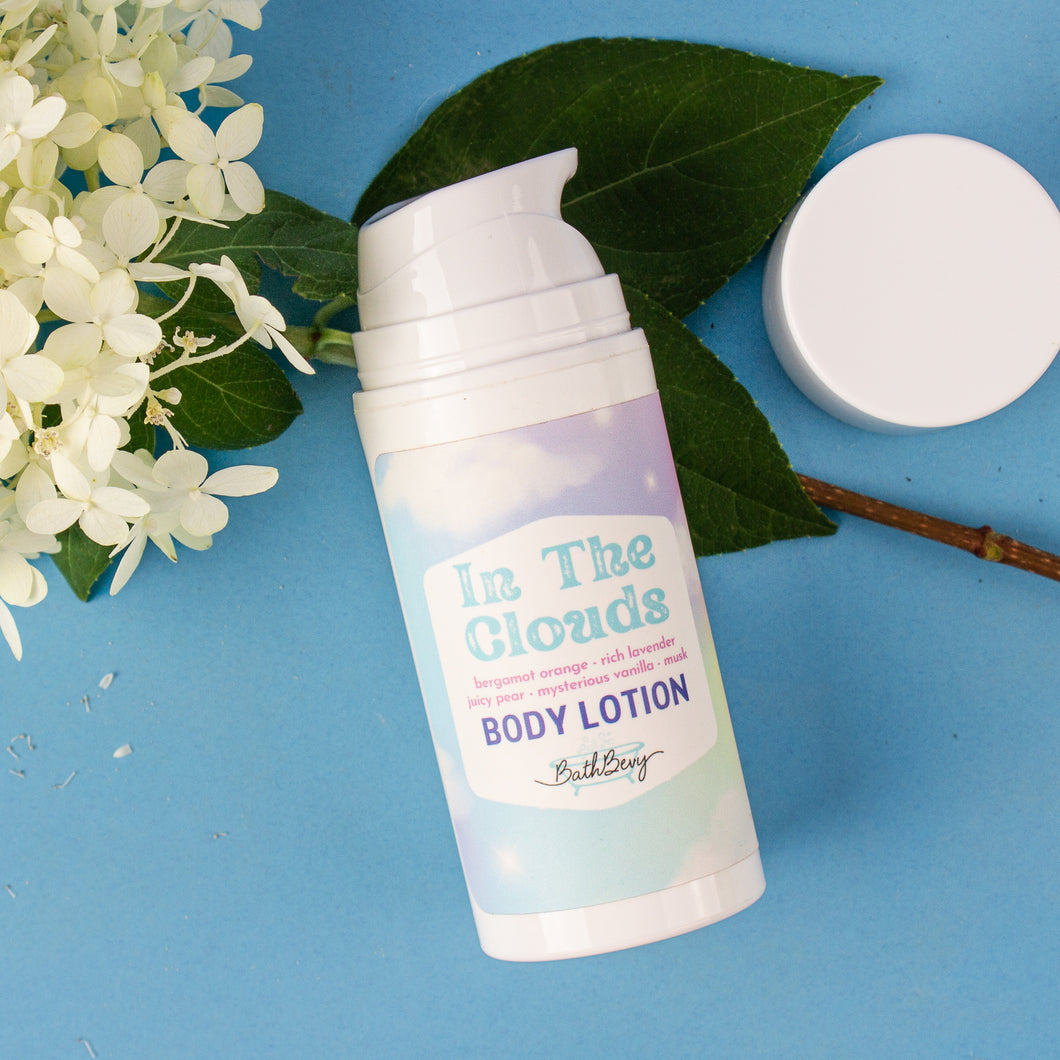 Body lotion bottle labeled 'In The Clouds' on a blue background with flowers and leaves.