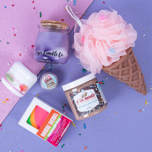 Load image into Gallery viewer, Assorted products including a candle, soap, and bath product on a colorful background