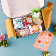 Load image into Gallery viewer, Open gift box with various items on a blue background