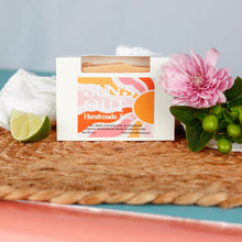 Load image into Gallery viewer, Handmade soap bar with a decorative label on a woven mat with flowers and a lime wedge.