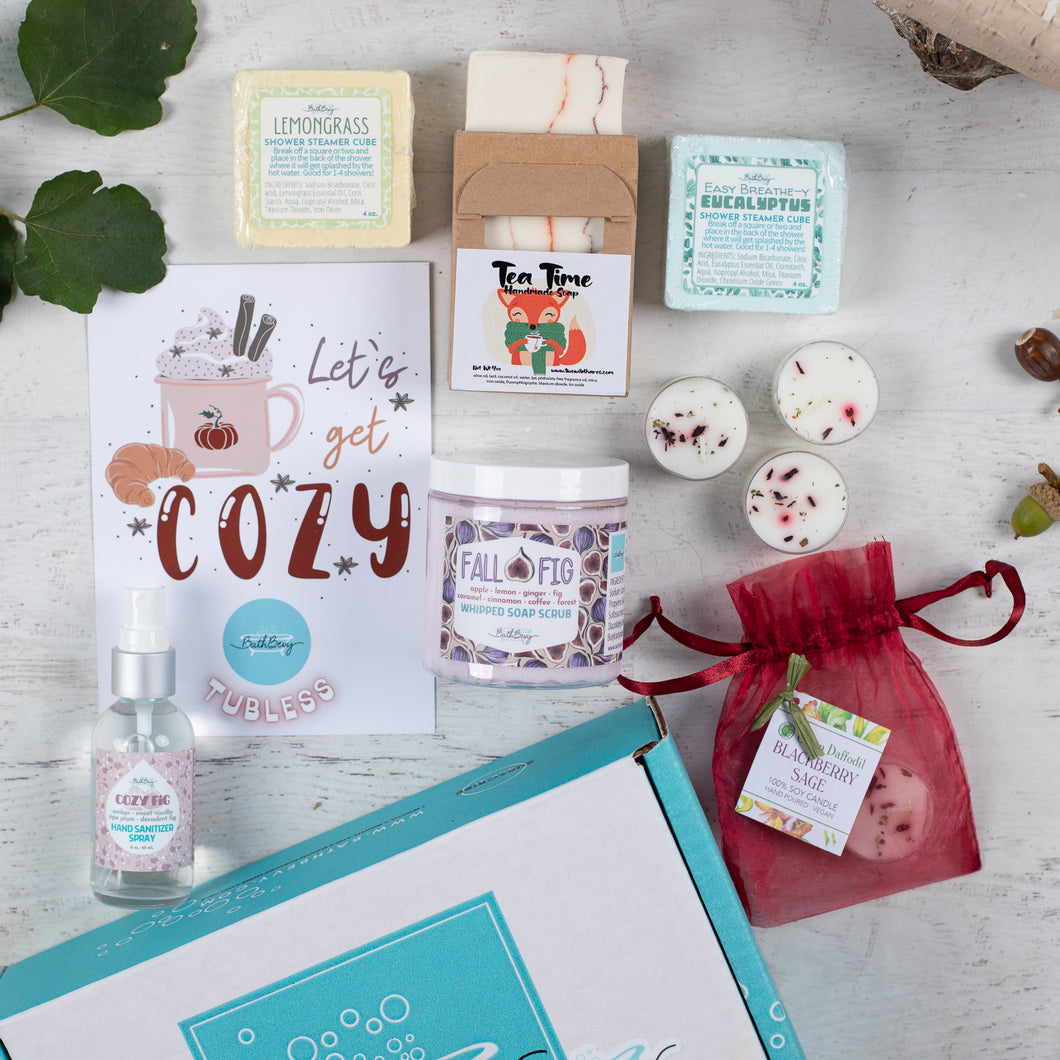 Collection of self-care products including candles, soap, and SHOWER STEAMERS on a wooden surface.