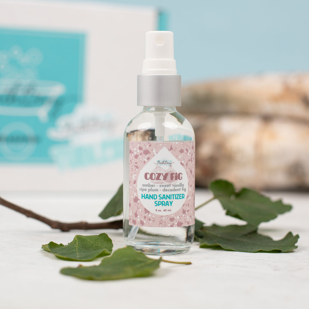 Hand sanitizer spray bottle with a floral label on a white surface with leaves.