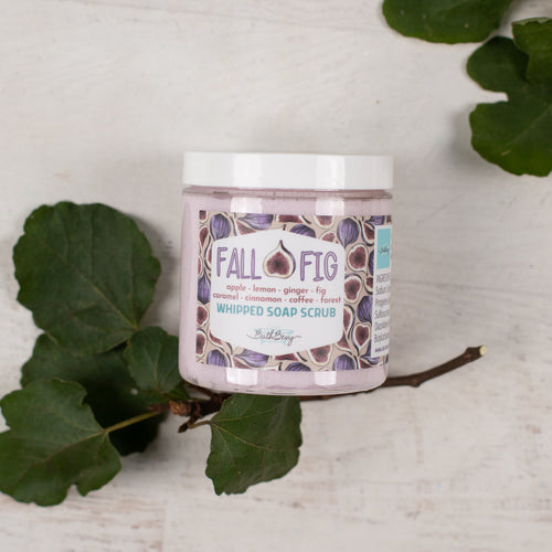 Jar of 'Fall Fig' whipped soap scrub with leaves on a light background