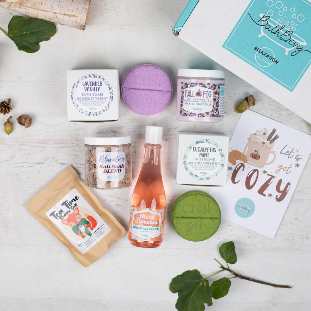 Collection of bath and body products on a light wooden surface with decorative elements.