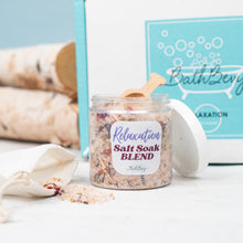 Load image into Gallery viewer, Jar of salt soak blend with a wooden spoon on a white surface, with &#39;Bath Berg&#39; branding in the background.